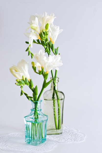 Il ramo di fresia bianca con fiori e boccioli in bottiglie decorative