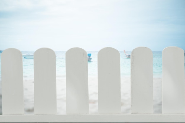 Il recinto di legno bianco ha isolato la sfocatura astratta della spiaggia e dello sfondo del ristorante dell'hotel di lusso che separa gli oggetti