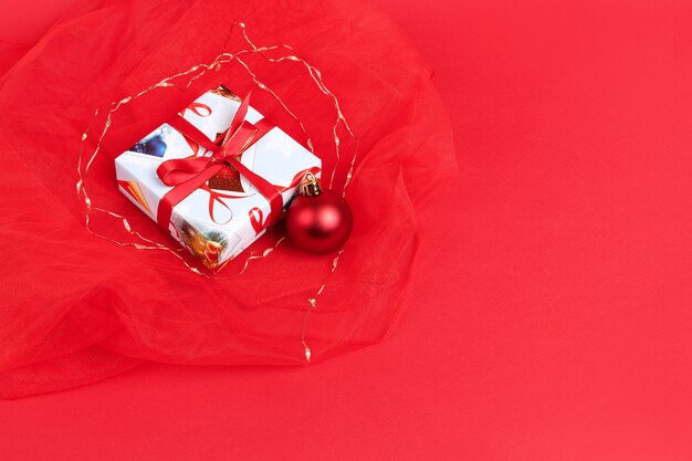 Il regalo di Capodanno e il giocattolo dell'albero di Natale su uno sfondo di Natale rosso