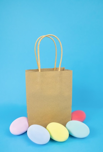 Il regalo e le uova del sacchetto di carta di Pasqua sono semplici multicolori su sfondo blu
