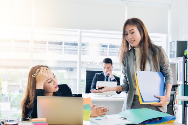 Il responsabile asiatico della donna di affari dà un ordine al segretario in un affare dell&#39;ufficio moderno