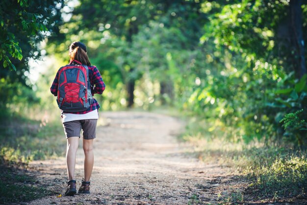 Il retro di una giovane donna escursionista con uno zaino che cammina su un sentiero di campagna