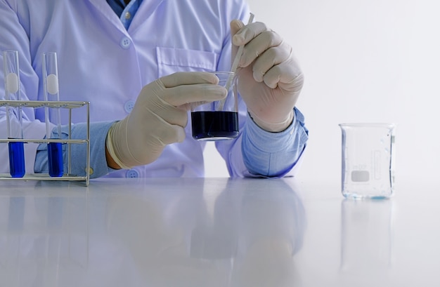 Il ricercatore di laboratorio medico o scientifico maschio esegue i test con liquido blu in laboratorio. Apparecchiature di laboratorio e concetti di esperimenti scientifici.