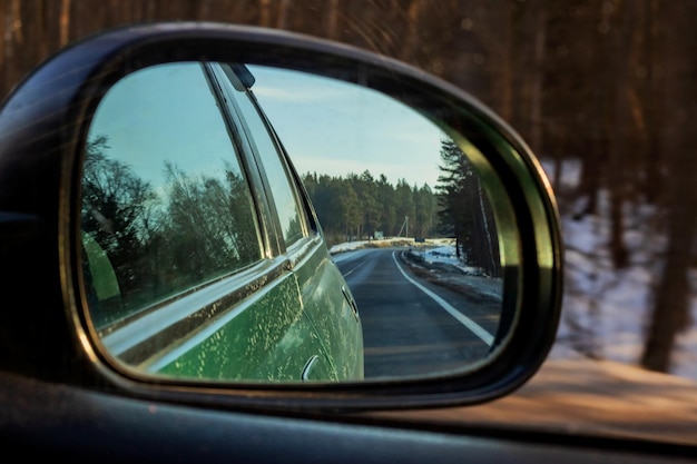 Il riflesso nello specchio della strada e della foresta dell'automobile