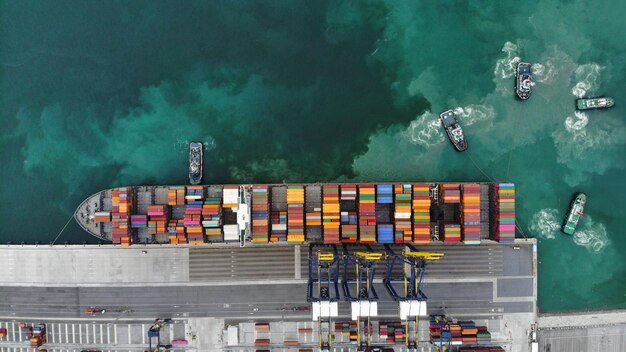 Il rimorchiatore che lavora nel porto del terminal internazionale prepara la nave portacontainer per la spedizione a soffitto del serbatoio del carico al cliente