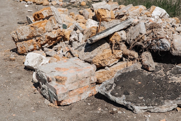 Il rinforzo sporge da un mucchio di pietra di mattoni e rifiuti di cemento inquinamento ambientale