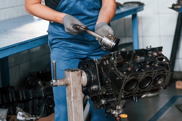 Il riparatore professionista in garage lavora con il motore di automobile rotto