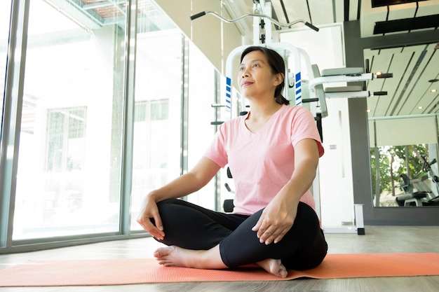 Il riscaldamento asiatico della donna di forma fisica prima di fa l'esercizio in palestra, yoga risolvente femminile di medio evo