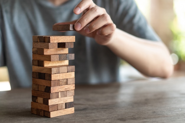 Il rischio accadrà. Ingegnere che gioca un gioco di blocchi di legno su legno