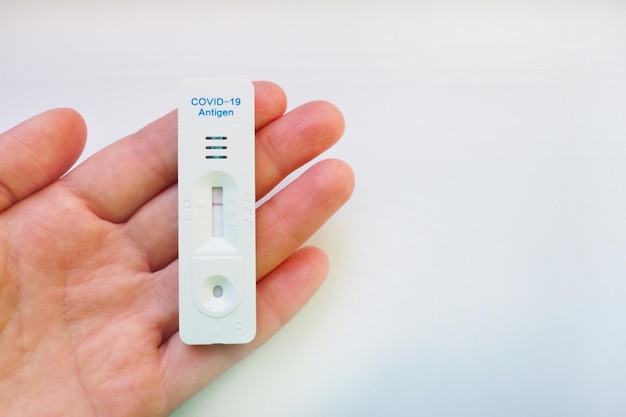 Il risultato del test per COVID-19 è negativo, non infetto, utilizzando apparecchiature per test rapidi. Test per il coronavirus sulla mano, sfondo bianco. Copia spazio. Concetto di test Infezione da malattia da coronavirus.