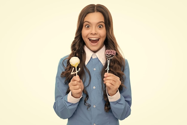 Il ritratto del bambino sorpreso ha lunghi capelli ricci tenere un dolce al cioccolato isolato su una pasticceria bianca