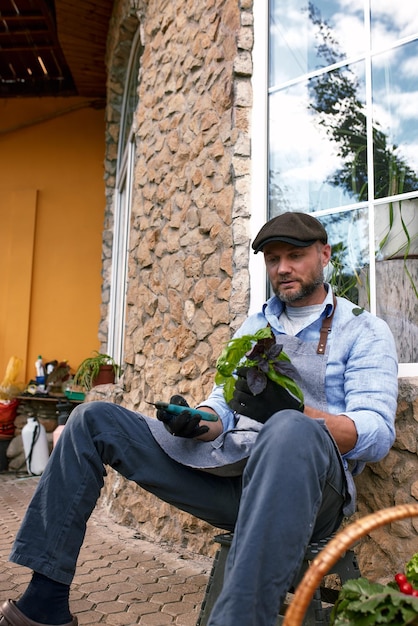 Il ritratto del bel giardiniere che indossa il cappello tiene le foglie di lattuga Giardinaggio biologico Il concetto di raccolta e agricoltura locale