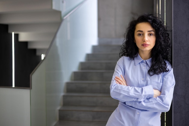 Il ritratto del capo femminile serio all'interno della donna di affari dell'ufficio della società di affari ha attraversato le braccia alla ricerca