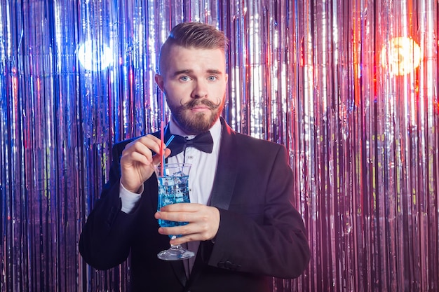 Il ritratto del concetto di festa e di festa del club dell'uomo bello elegante in un vestito costoso tiene il blu