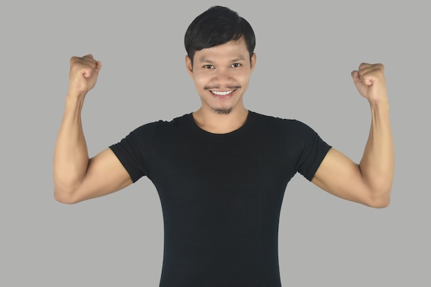 Il ritratto del giovane in maglietta nera con le mani mostra il muscolo isolato su fondo bianco