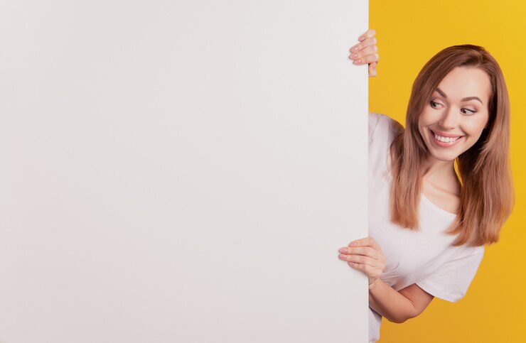 Il ritratto del primo piano della ragazza del consigliere positivo guarda tenere il tabellone per le affissioni bianco