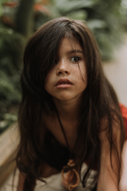 Il ritratto del primo piano la bambina indiana di mowgli in un perizoma si nasconde nascondendosi nel fondo della foresta dei tropici