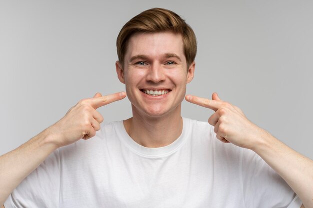 Il ritratto dell'uomo allegro felice punta il dito indice al sorriso mostra i denti bianchi