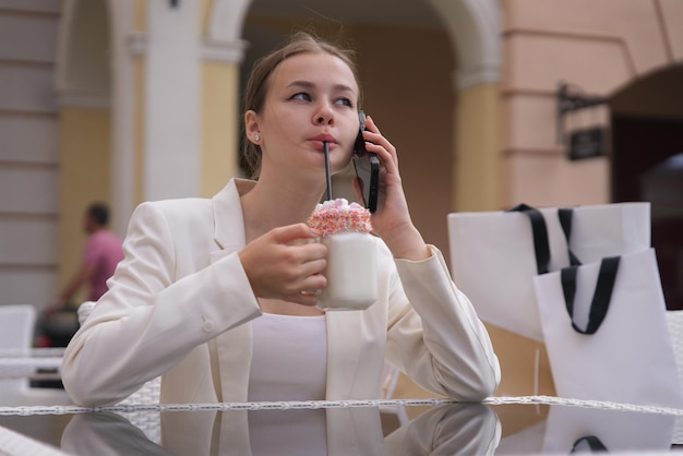 Il ritratto della bella donna teenager dell'adolescente teenager della ragazza alla moda positiva felice sta sorridendo divertendosi nel centro commerciale durante lo shopping che tiene in mano i sacchetti di carta della spesa