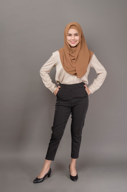 Il ritratto della donna con hijab sta sorridendo su gray