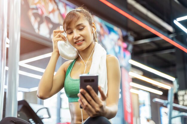 Il ritratto della donna di sport che usando il cellulare con si rilassa dopo l'esercizio in palestra