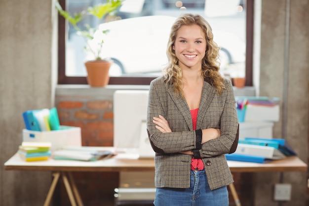 Il ritratto della donna sorridente sicura con le armi ha attraversato in ufficio