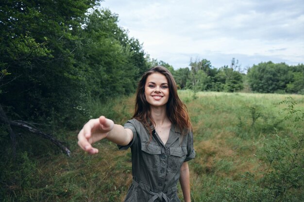 Il ritratto della donna sulla natura in una tuta verde sorride con una mano tesa