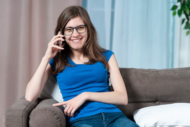 Il ritratto della giovane bella donna graziosa gioiosa della ragazza positiva felice sta parlando sul suo cellulare