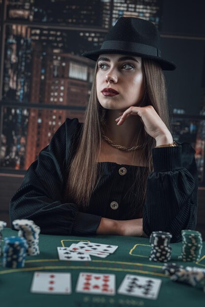 Il ritratto della giovane donna alla moda elegante con la carta e le fiches del casinò gioca il gioco della mazza