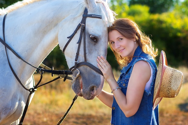 Il ritratto della ragazza con il cappello che abbraccia un cavallo