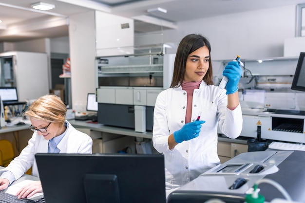 Il ritratto della scienziata con una pipetta analizza un liquido per estrarre il DNA e le molecole nelle provette in laboratorio Concetto di ricercabiochimica medicina farmaceutica