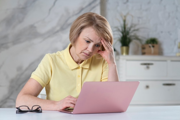 Il ritratto di bella donna anziana anziana stanca e matura donna adulta freelance sta lavorando su laptop