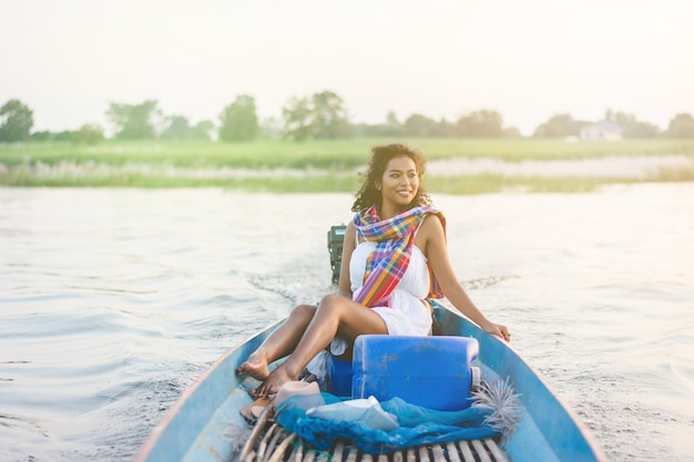 Il ritratto di bella donna asiatica che si siede sul peschereccio, gode di all&#39;aperto naturale nel lago