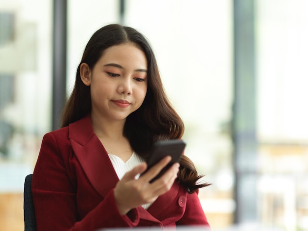 Il ritratto di bella donna asiatica usa l'internet banking del messaggio di testo del telefono cellulare sullo smartphone