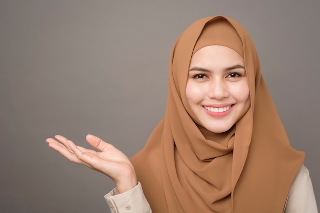 Il ritratto di bella donna con hijab sta mostrando qualcosa sulla sua mano