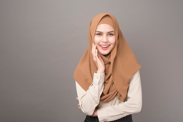 Il ritratto di bella donna con hijab sta sorridendo sulla parete grigia