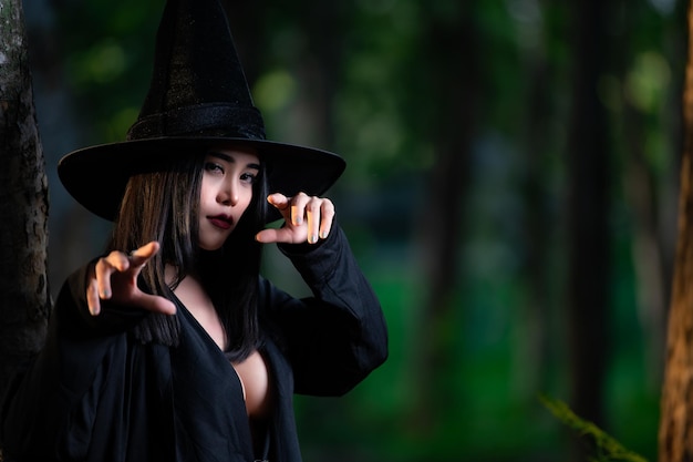 Il ritratto di bella donna sexy asiatica indossa il costume da strega nera con il concetto di festival di Halloween della scopa