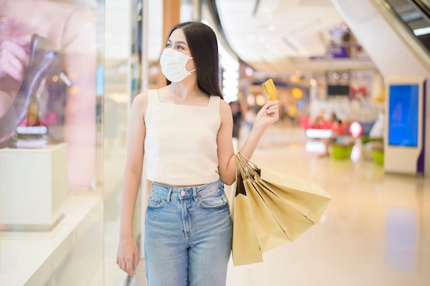 Il ritratto di bella donna sta indossando la maschera nel centro commerciale