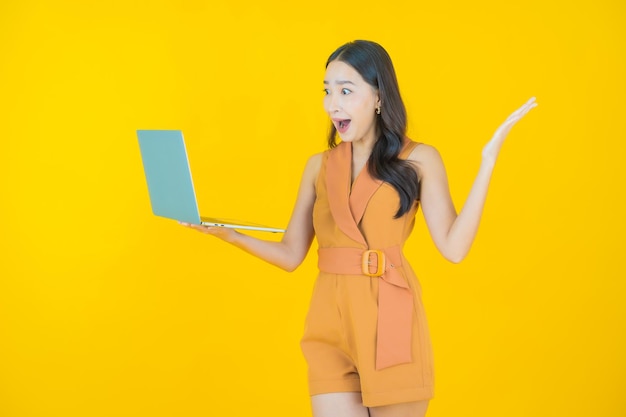 Il ritratto di bella giovane donna asiatica sorride con il computer portatile del computer
