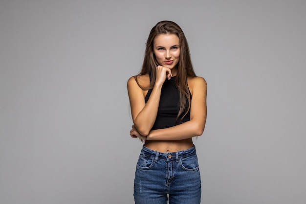 Il ritratto di bella giovane donna sveglia pensa a una nuova idea e guarda qualcosa su sfondo grigio