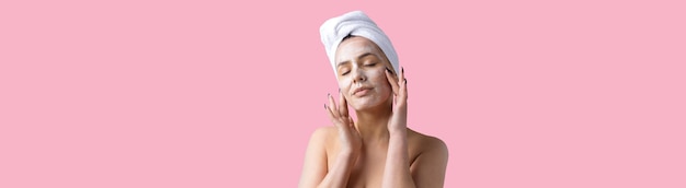 Il ritratto di bellezza della donna con un asciugamano bianco sulla testa applica la crema sul viso Detergente per la cura della pelle eco-cosmetico biologico spa relax concetto