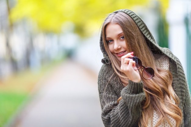 Il ritratto di bello modello femminile in autunno copre all'aperto