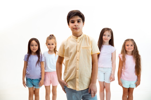 Il ritratto di felice carino ragazzini ragazzo e ragazze in eleganti abiti casual che guarda l'obbiettivo contro il muro bianco