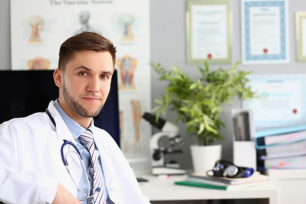 Il ritratto di giovane medico si siede nell'ufficio della clinica