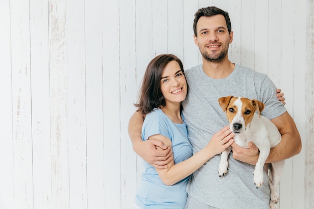 Il ritratto di giovani coppie della famiglia si abbraccia e tiene il loro animale domestico preferito