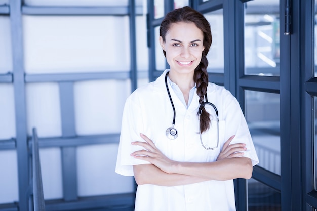 Il ritratto di medico femminile felice che sta con le armi ha attraversato in ospedale