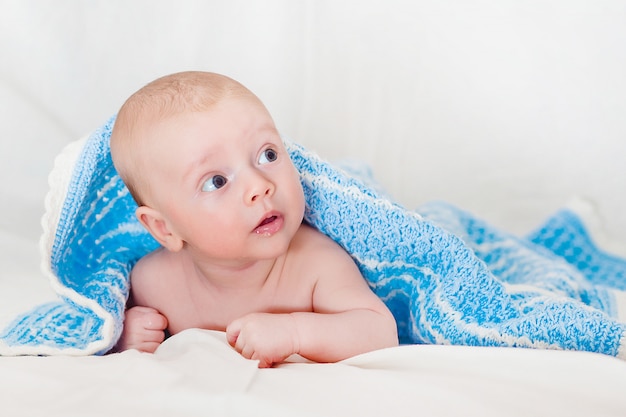 Il ritratto di un bambino infantile sorridente sveglio che striscia in un pannolino, bambino di due mesi tiene la testa