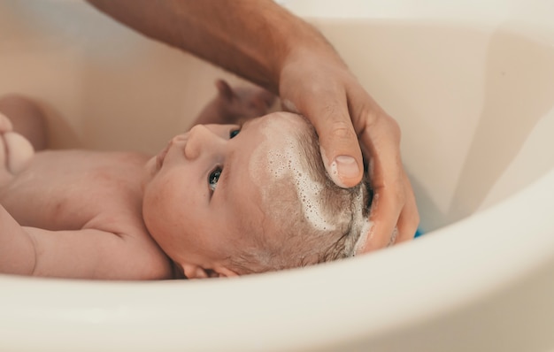 Il ritratto di un bambino viene lavato da suo padre usando la vasca a casa