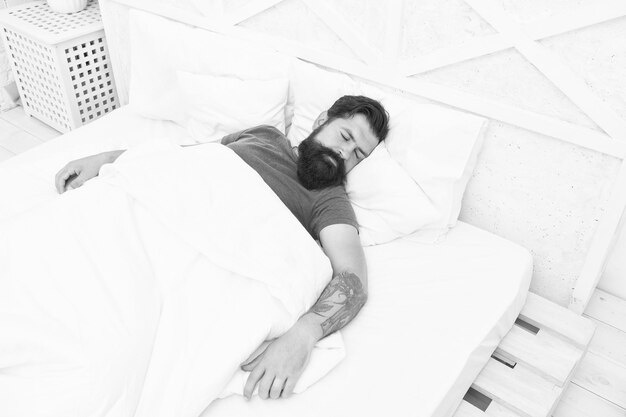 Il ritratto di un hipster maschio brutale che dorme sul letto si rilassa