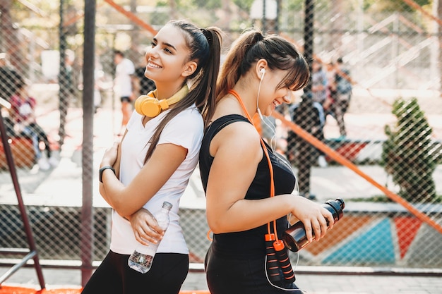 Il ritratto di un istruttore femminile giovane carino e la sua ragazza in un parco sportivo facendo esercizi per perdere peso.